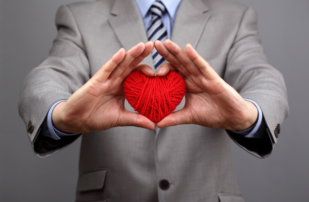 Man in business suit hold hands around red heart