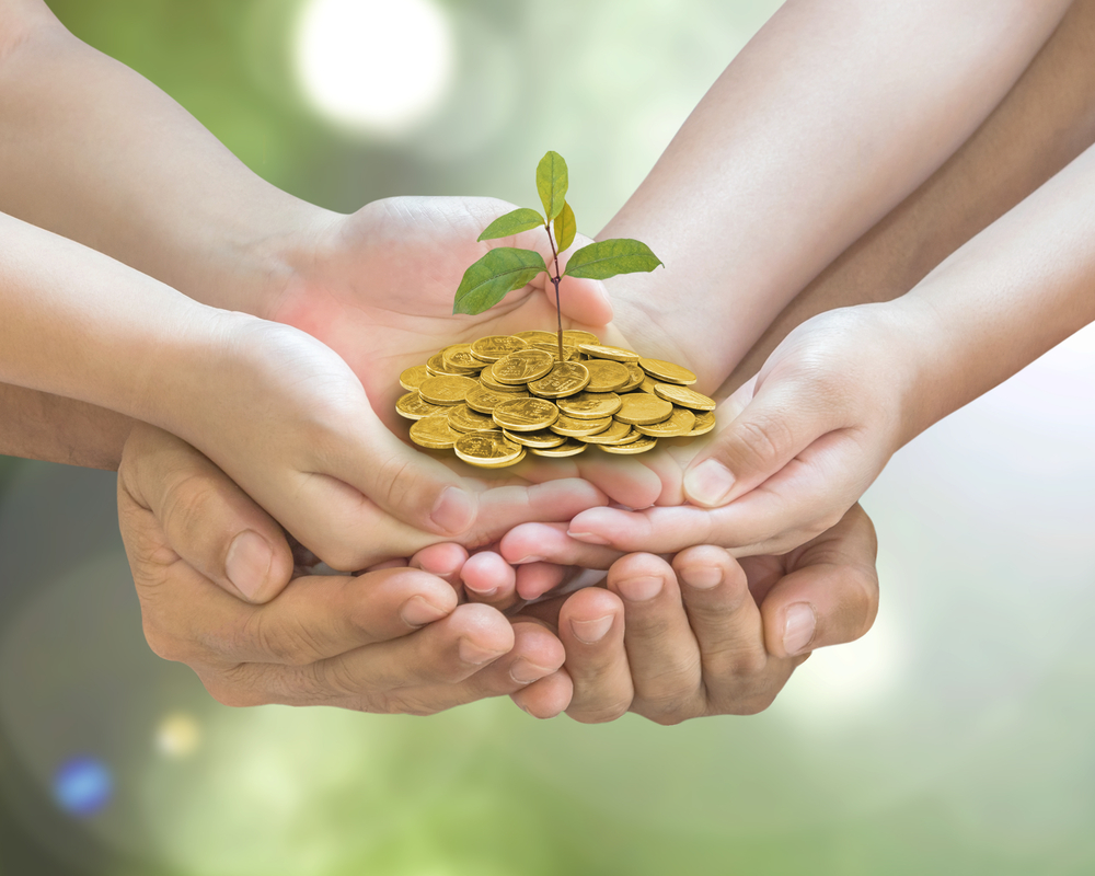 A family holding a stack of change with a plant growing out of it.