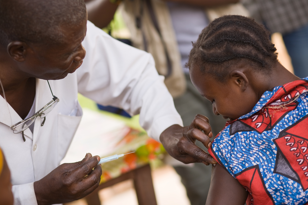 A photo of a medical professional in the Democratic Republic of Congo administering a vaccine to a child.